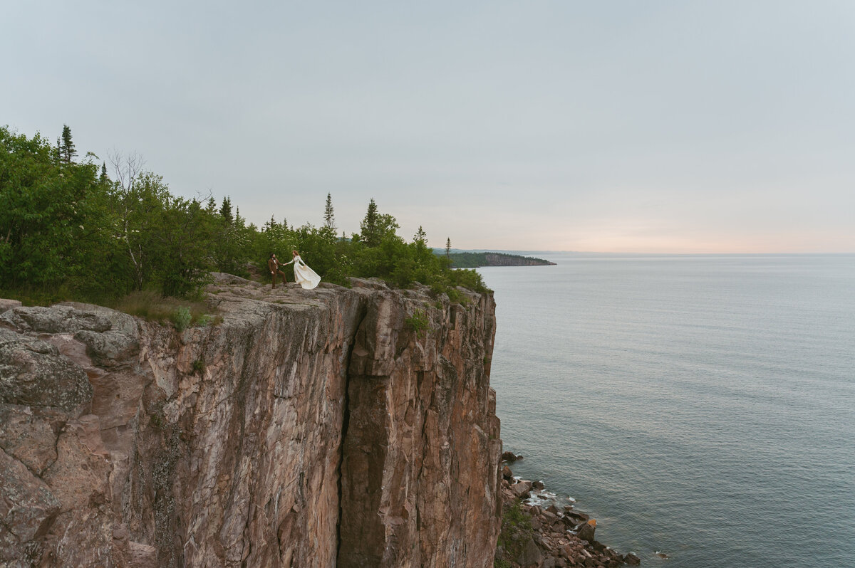 Couple stand on the cliffside at the sunrise