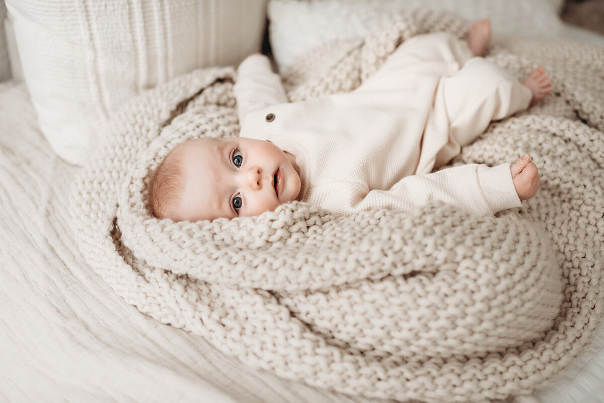 baby boy lying on knit blanket looking at denver milestone photographer Alyssum Hutchison
