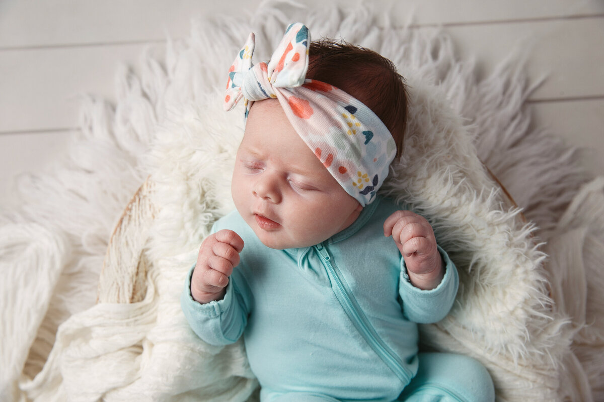 Cute baby girl in a blue sleeperand floral headband