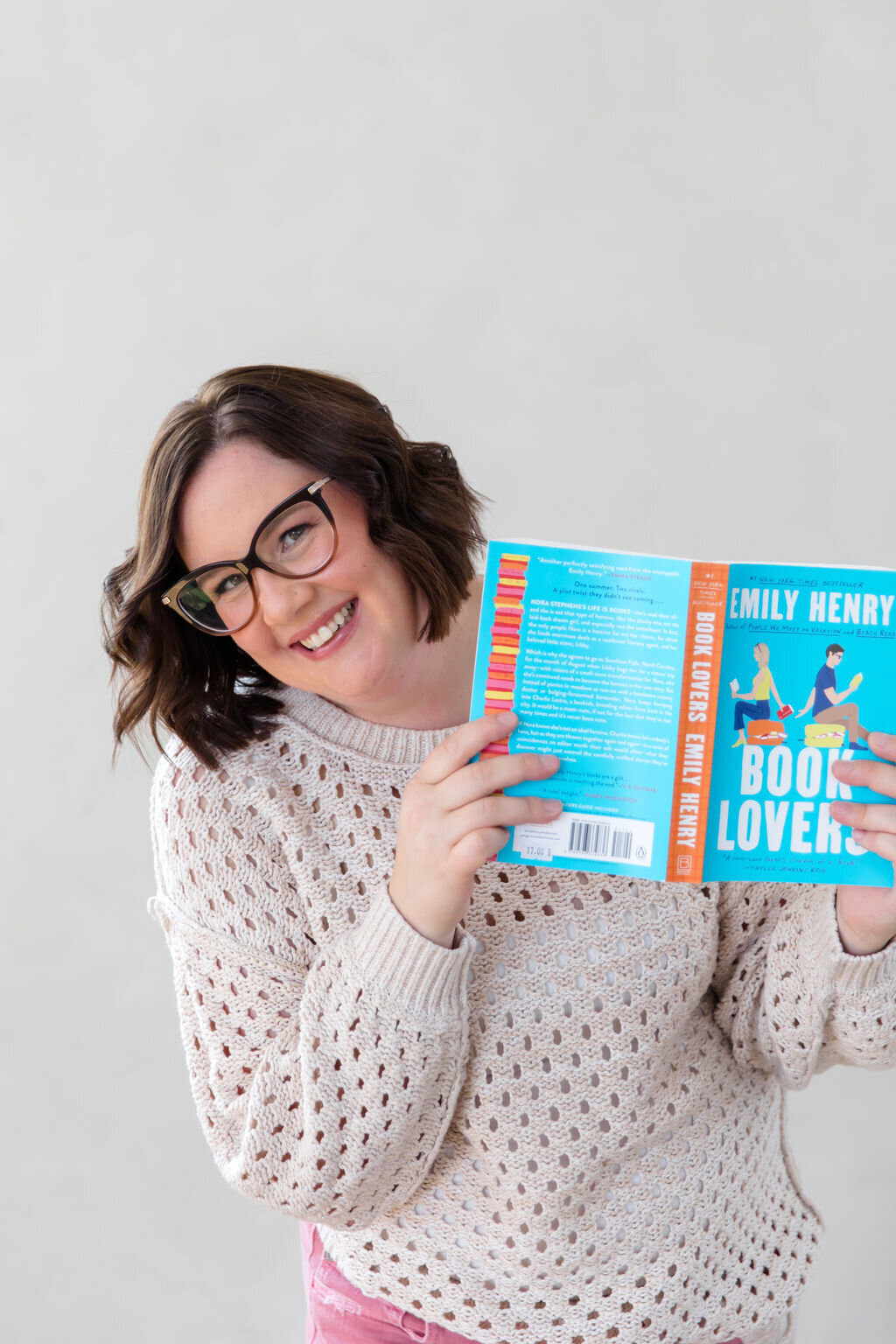 Bookstore owner Sara Gillis holding a book and smiling