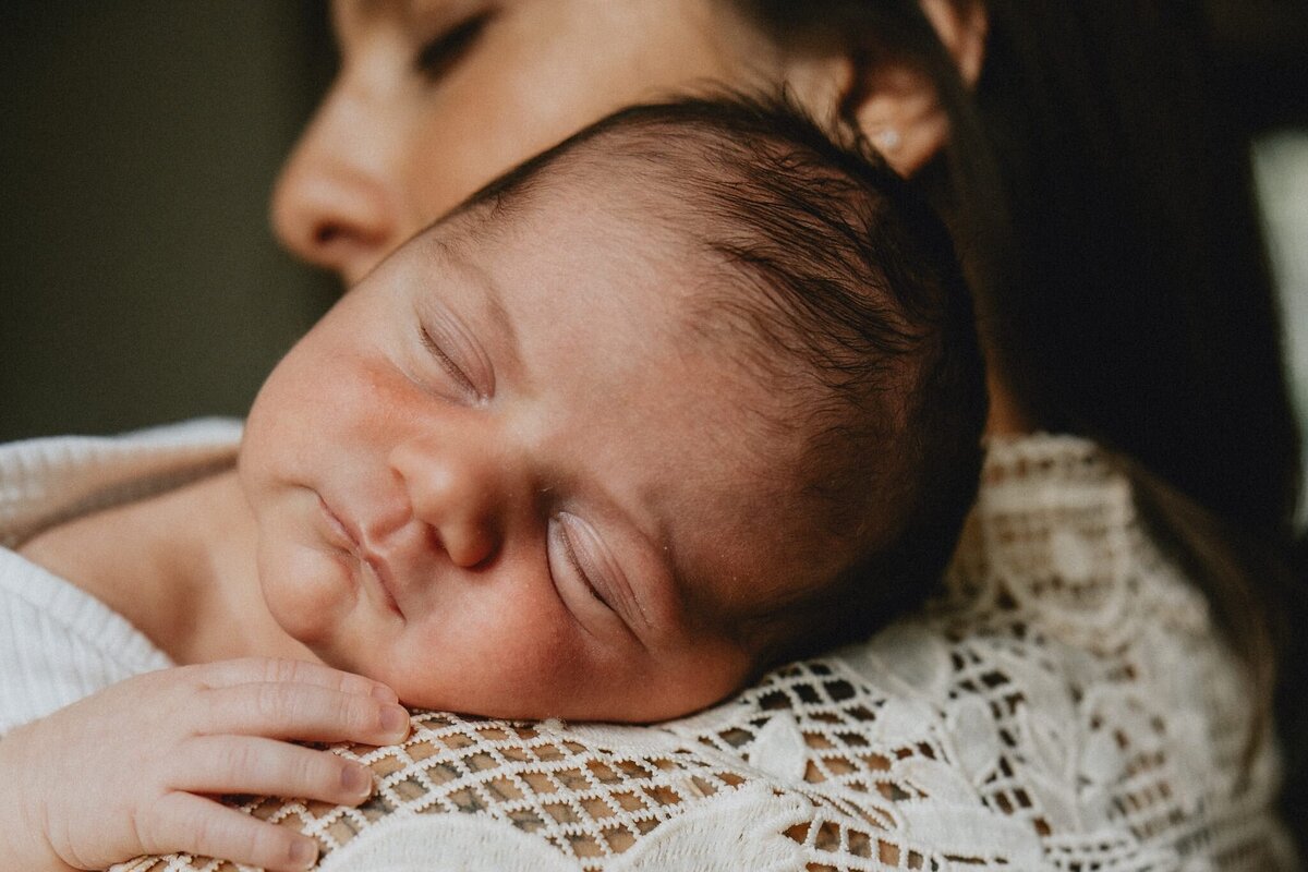 Cozy in home newborn photo of a mother kissing her newborn baby boy