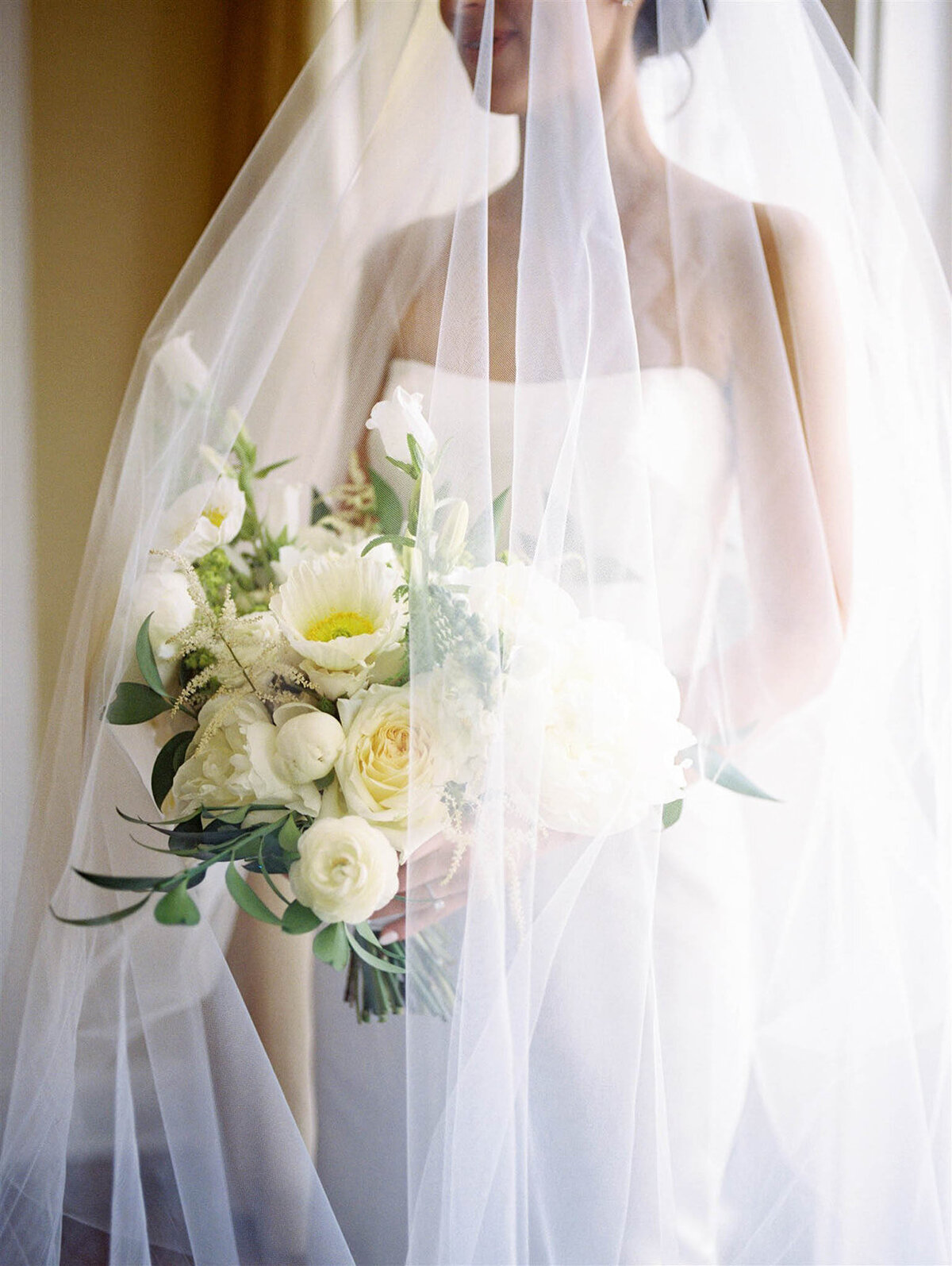 bride holding her bouquet under her veil