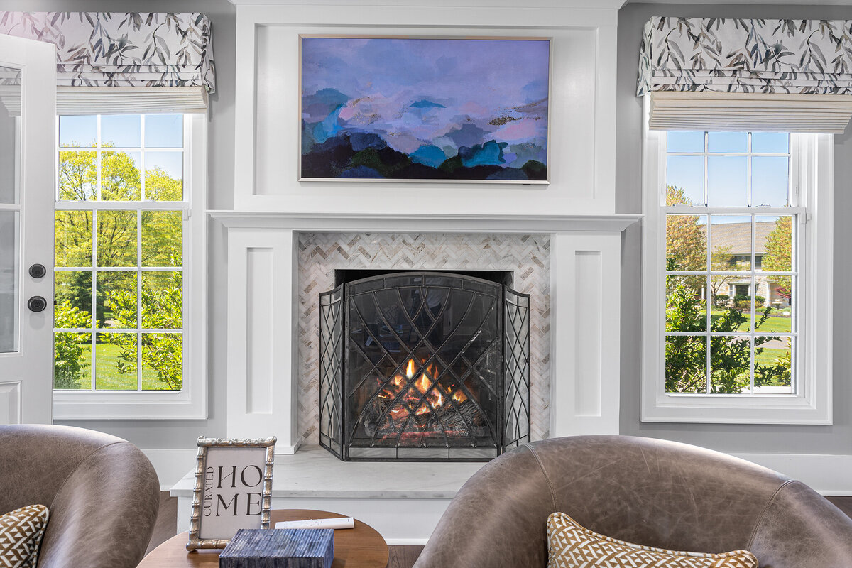 framed TV with mountain picture and fireplace below