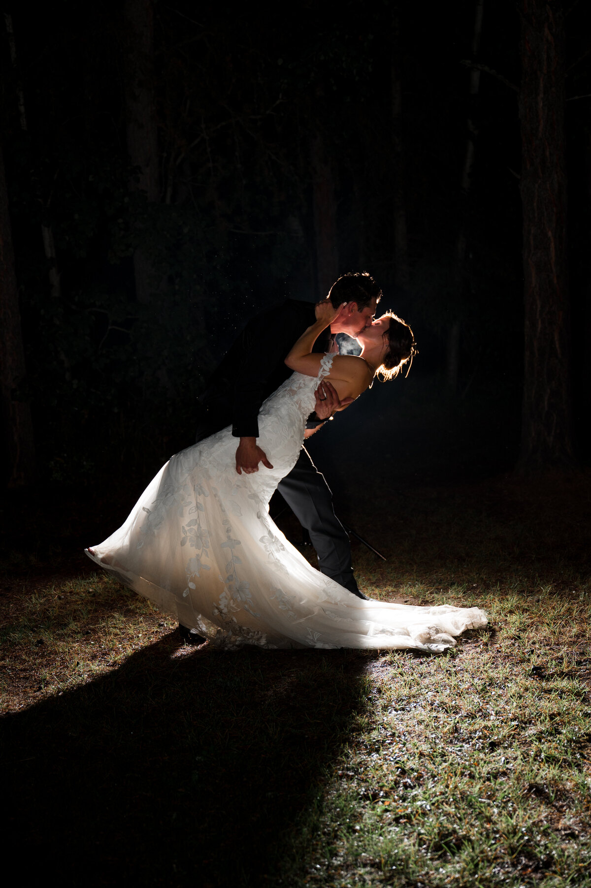 backlit artistic photo of bride and groom kissing