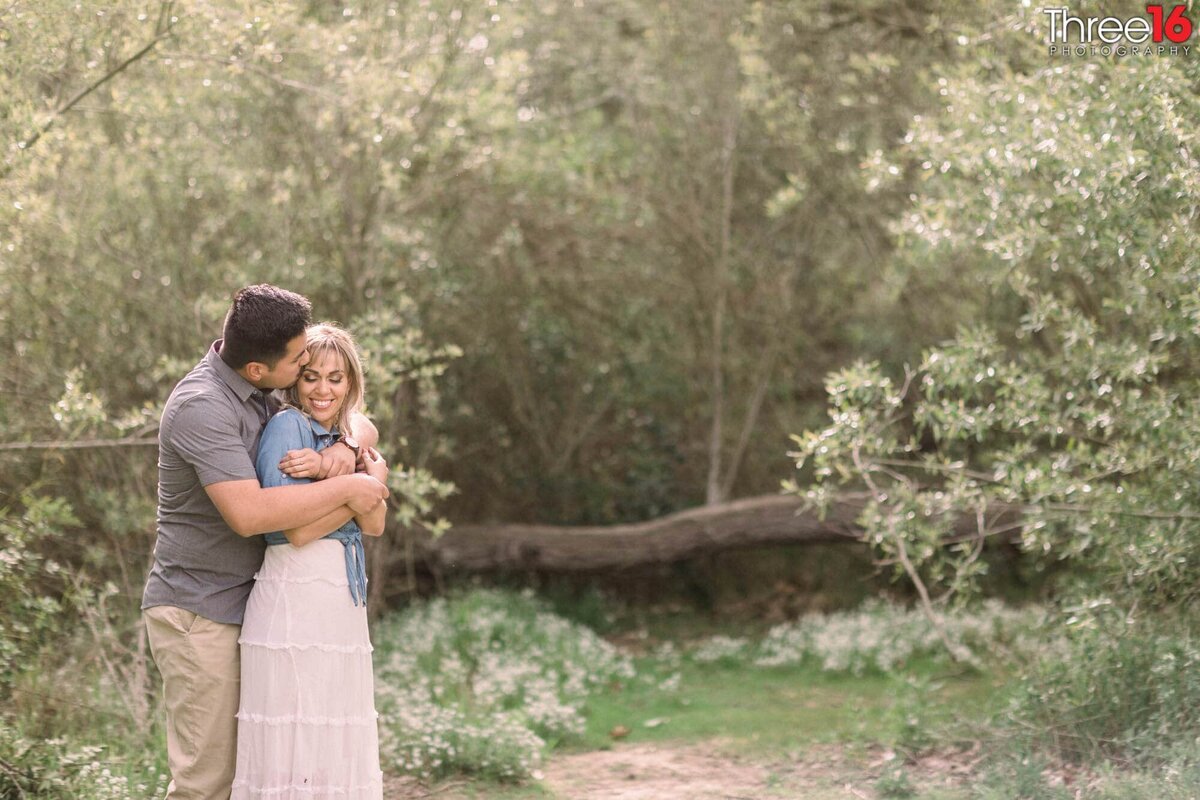 Groom to be lovingly embraces his Bride from behind at the Talbert Regional Park