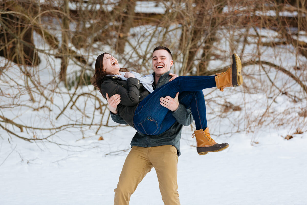 A person holding up their partner while they stand in the snow.