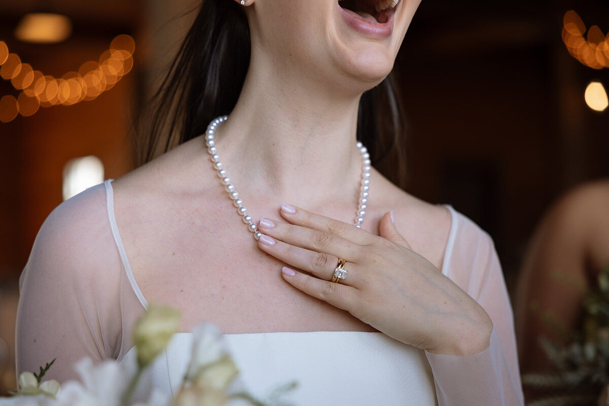 Close-up of the bride holding a white rose bouquet with soft peach and green accents.