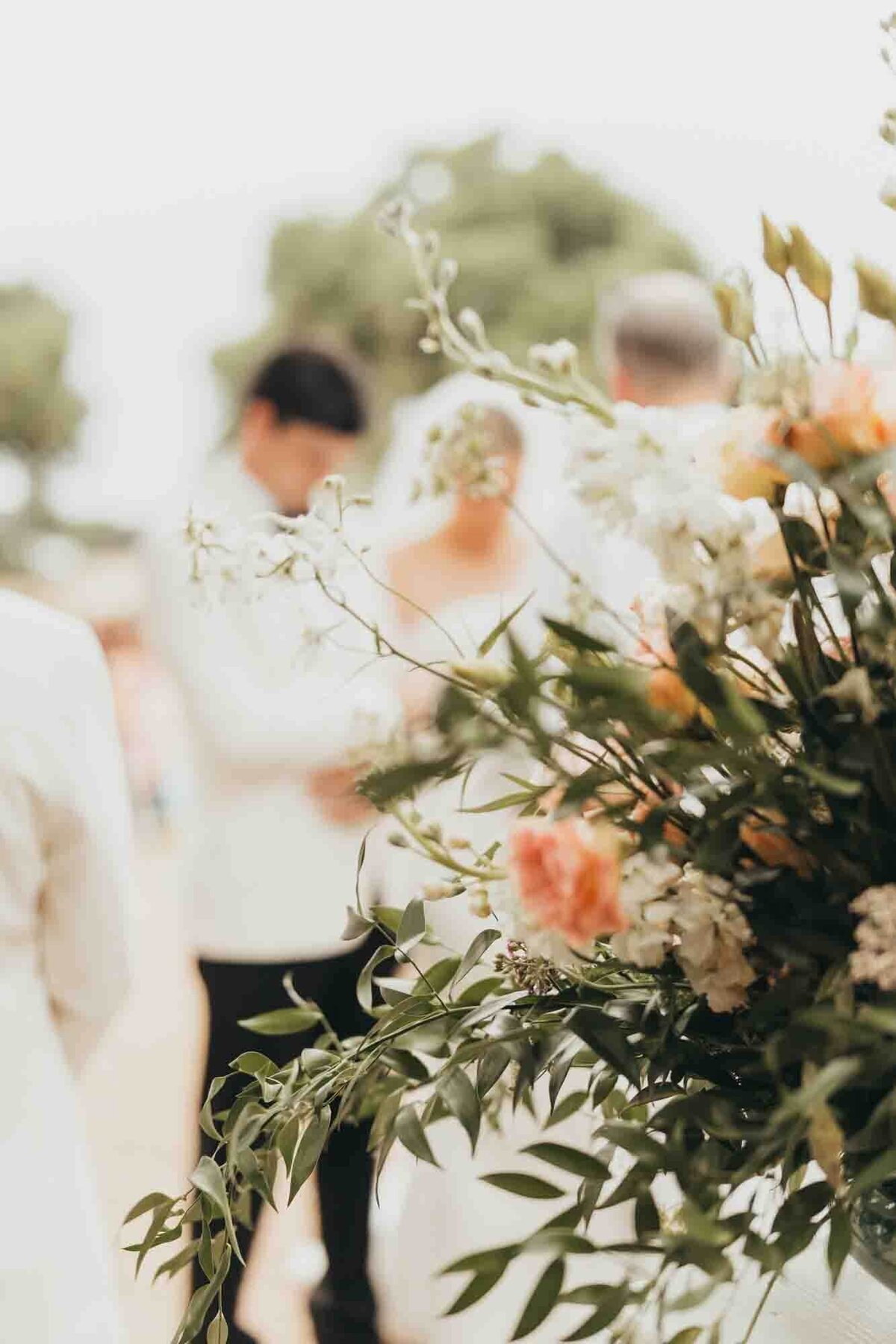 florals in focus with bride and groom in background of image.