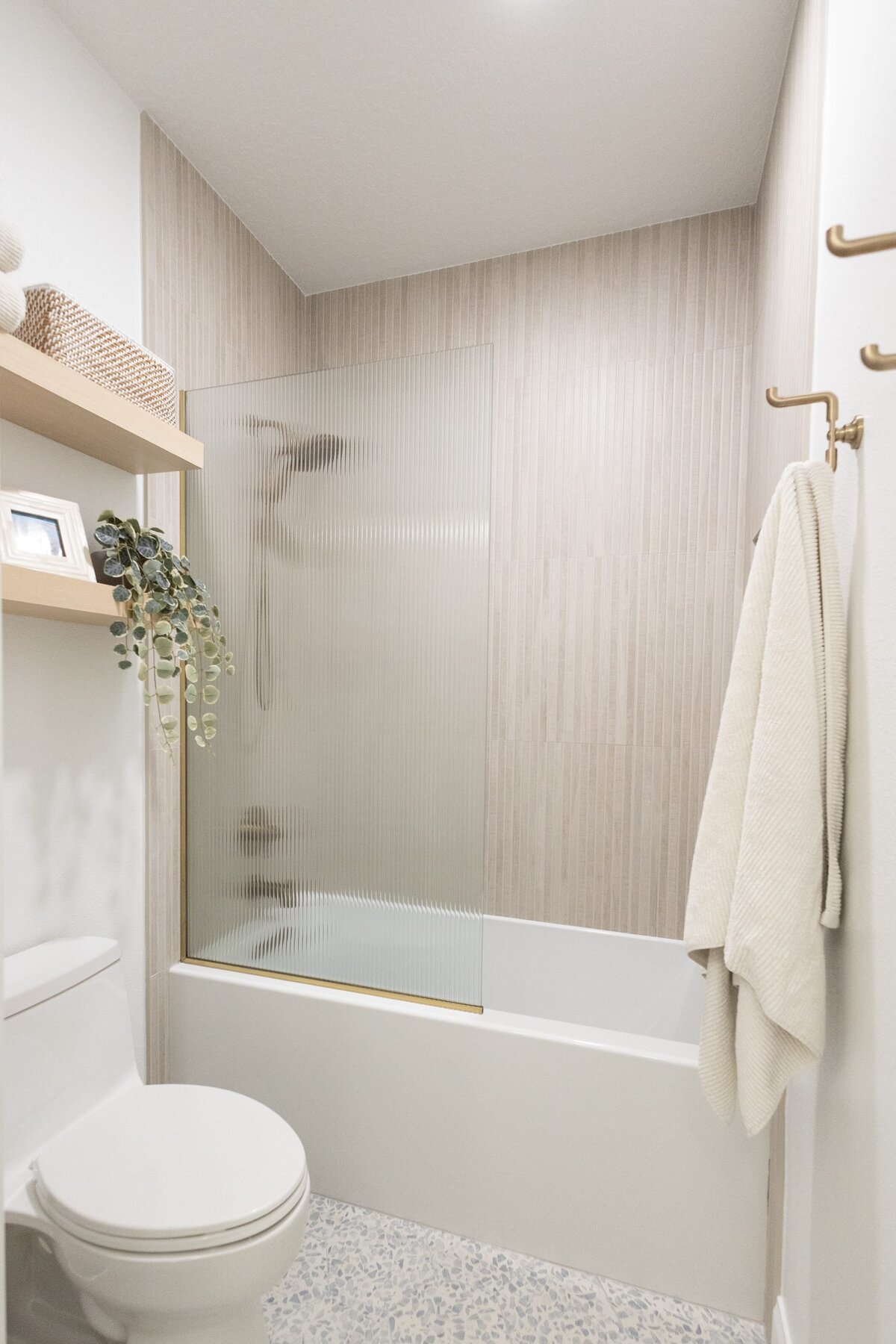 dewine design orlando interior designer contemporary coastal teen bathroom shower with neutral tile and wooden floating shelves