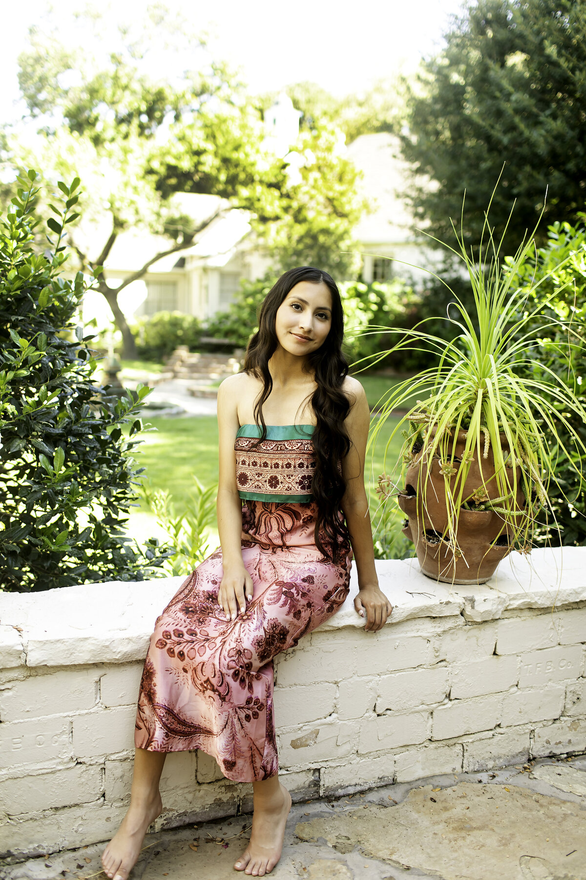 A senior exuding elegance as she stands near the enchanting stone features of Chandor Gardens, framed by the lush gardens and peaceful surroundings