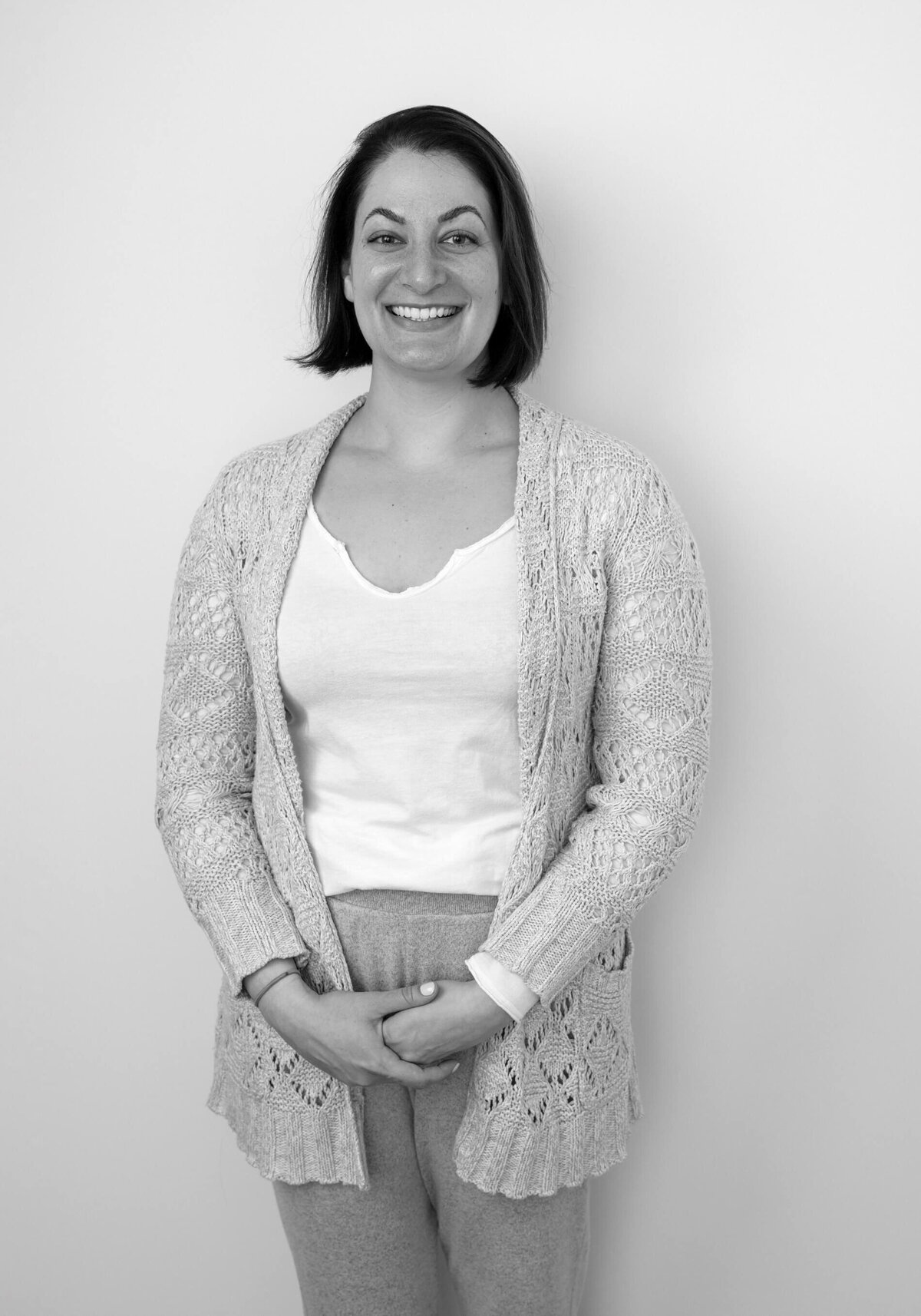 Studio before shot of a woman in a cardigan over a tank top, gazing calmly at the camera.