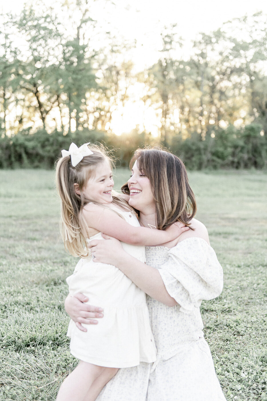 A mother and daughter hug in a field at sunset by Nashville family photographer