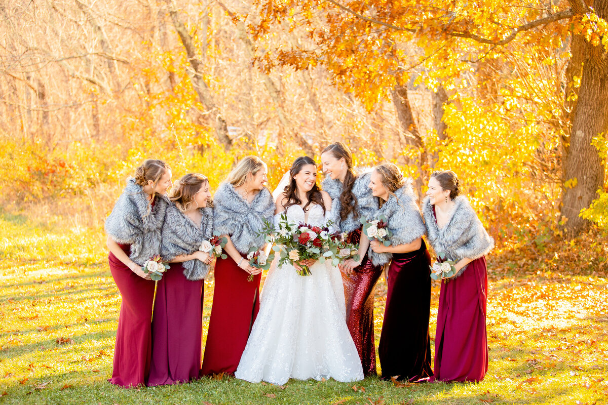 Bride laughs with her bridesmaids  during their fall wedding.