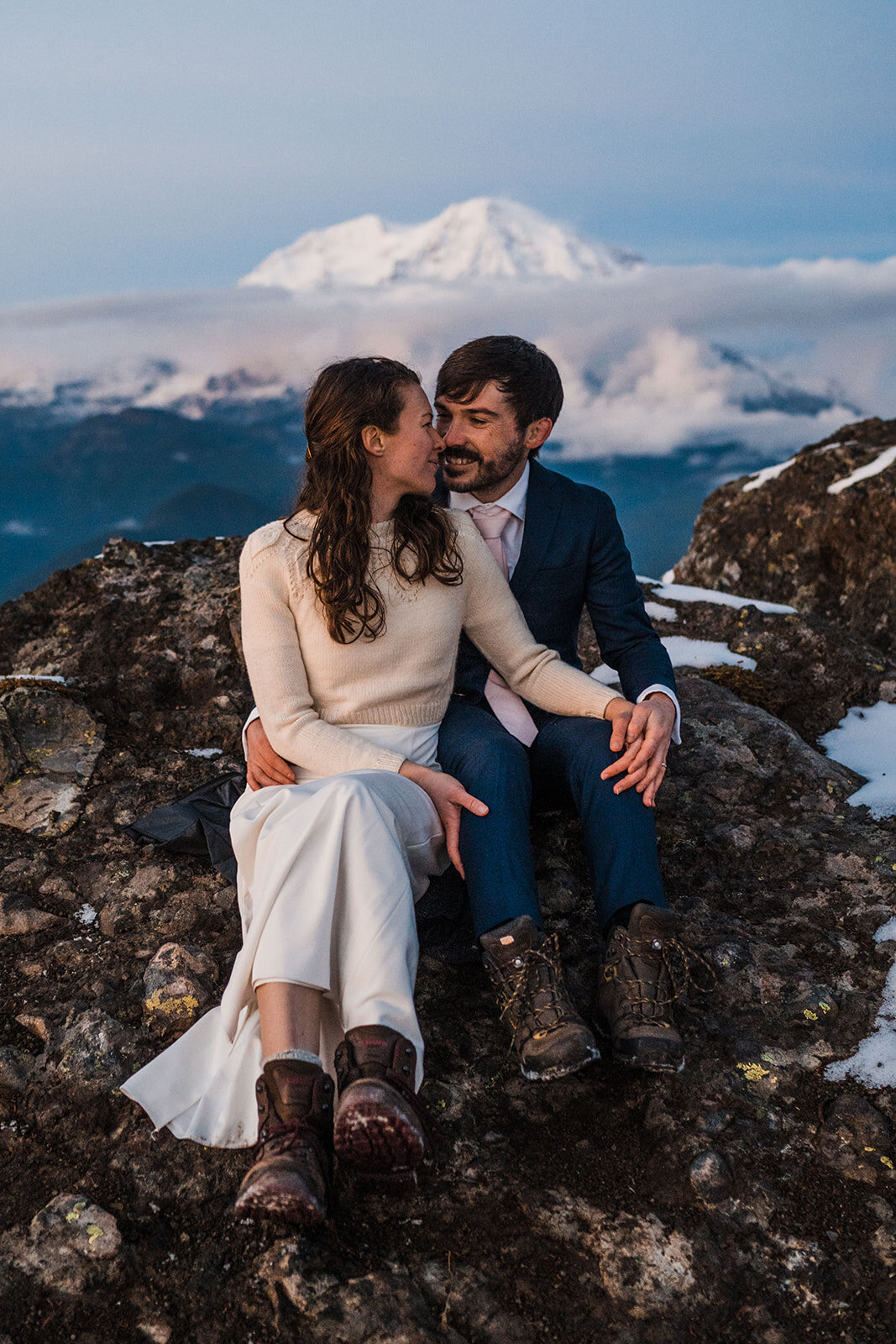 Bride & groom snuggling up on rocks overlooking Mount Rainier during hiking elopement!
