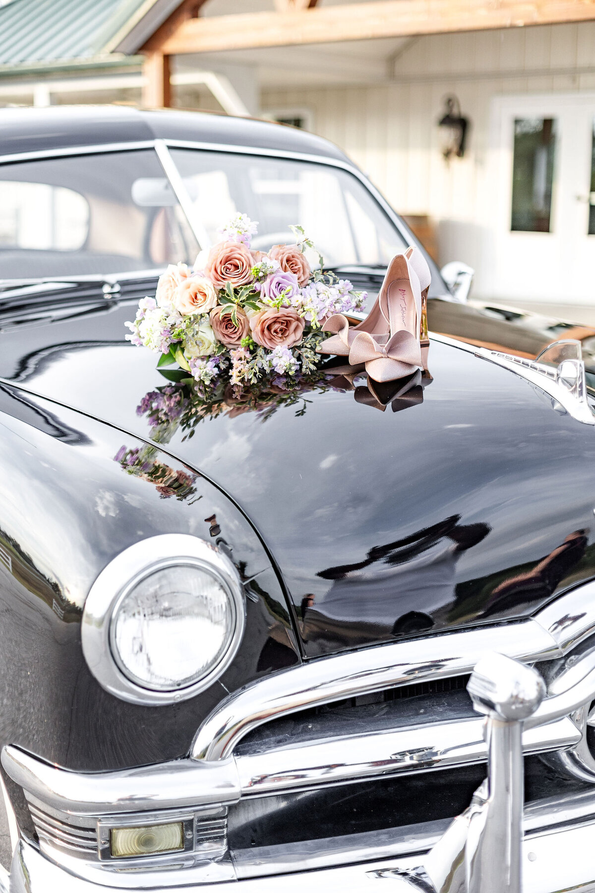 A vintage car adorned with a floral arrangement on the hood, set outside Willow and Stone Events in Mocksville, NC.