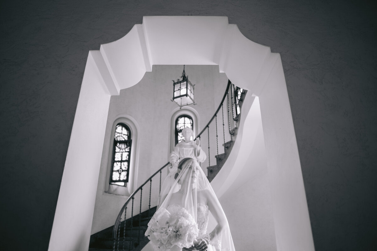 Bride under an elegant archway descending a spiral staircase during a Miami wedding.