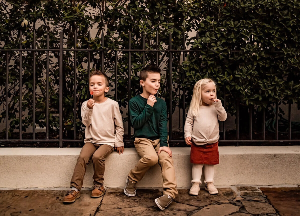 Three kids enjoying lollipops on a Charleston cobble street during a relaxed lifestyle family session 