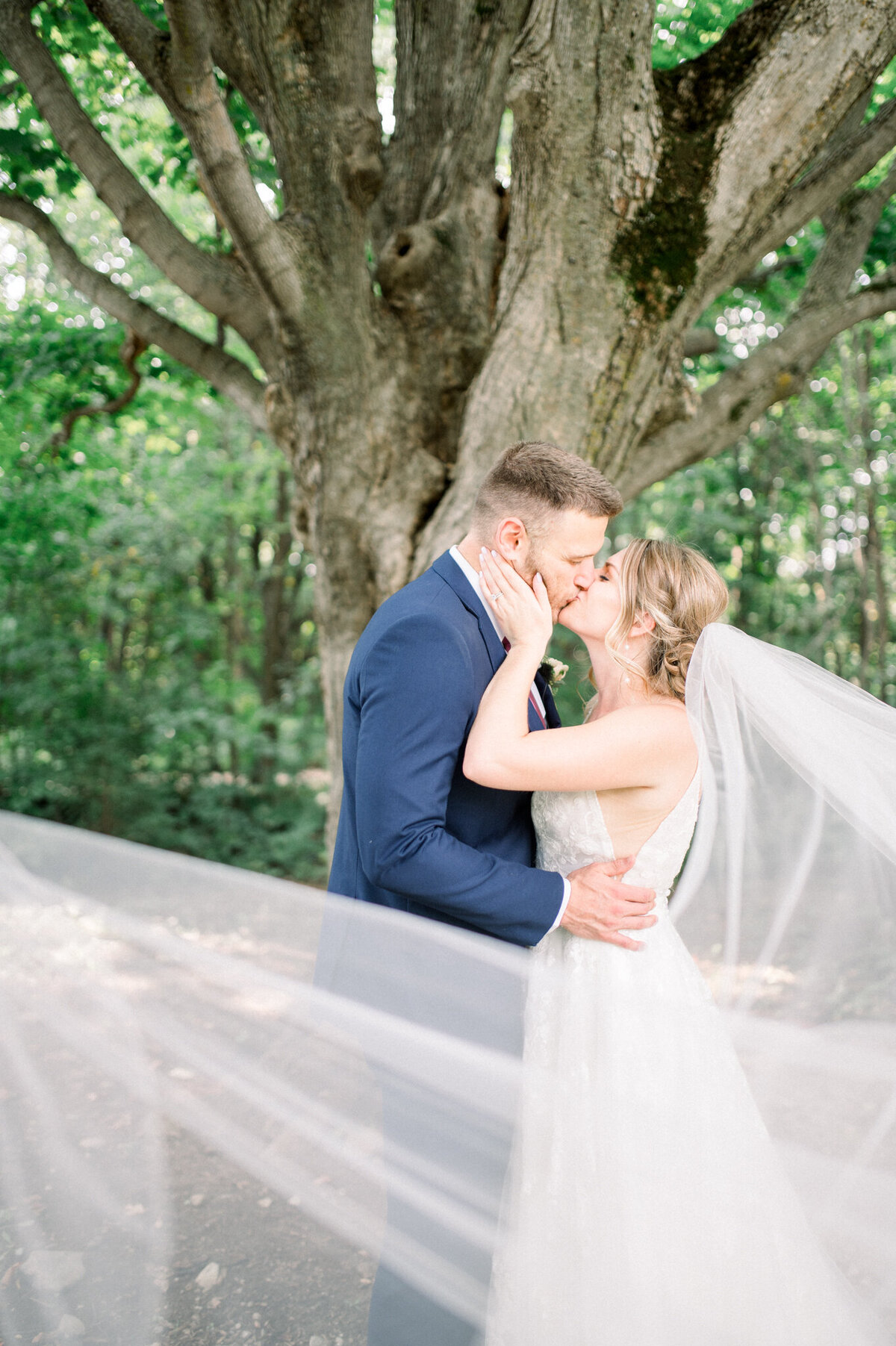 Bride and groom kissing with the veil blowing across the photo captured by Niagara wedding photographer Kristine Marie Photography