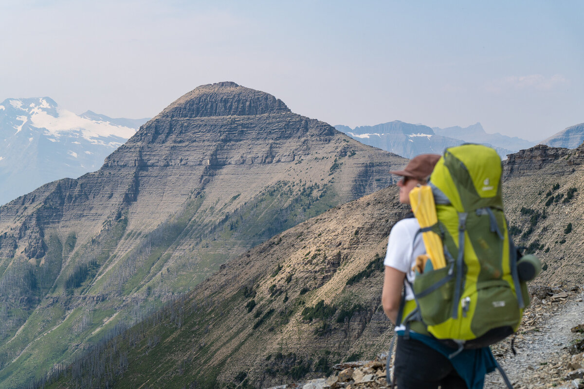 A female hiker looks over the Continental Divide in Glacier National Park while backpacking