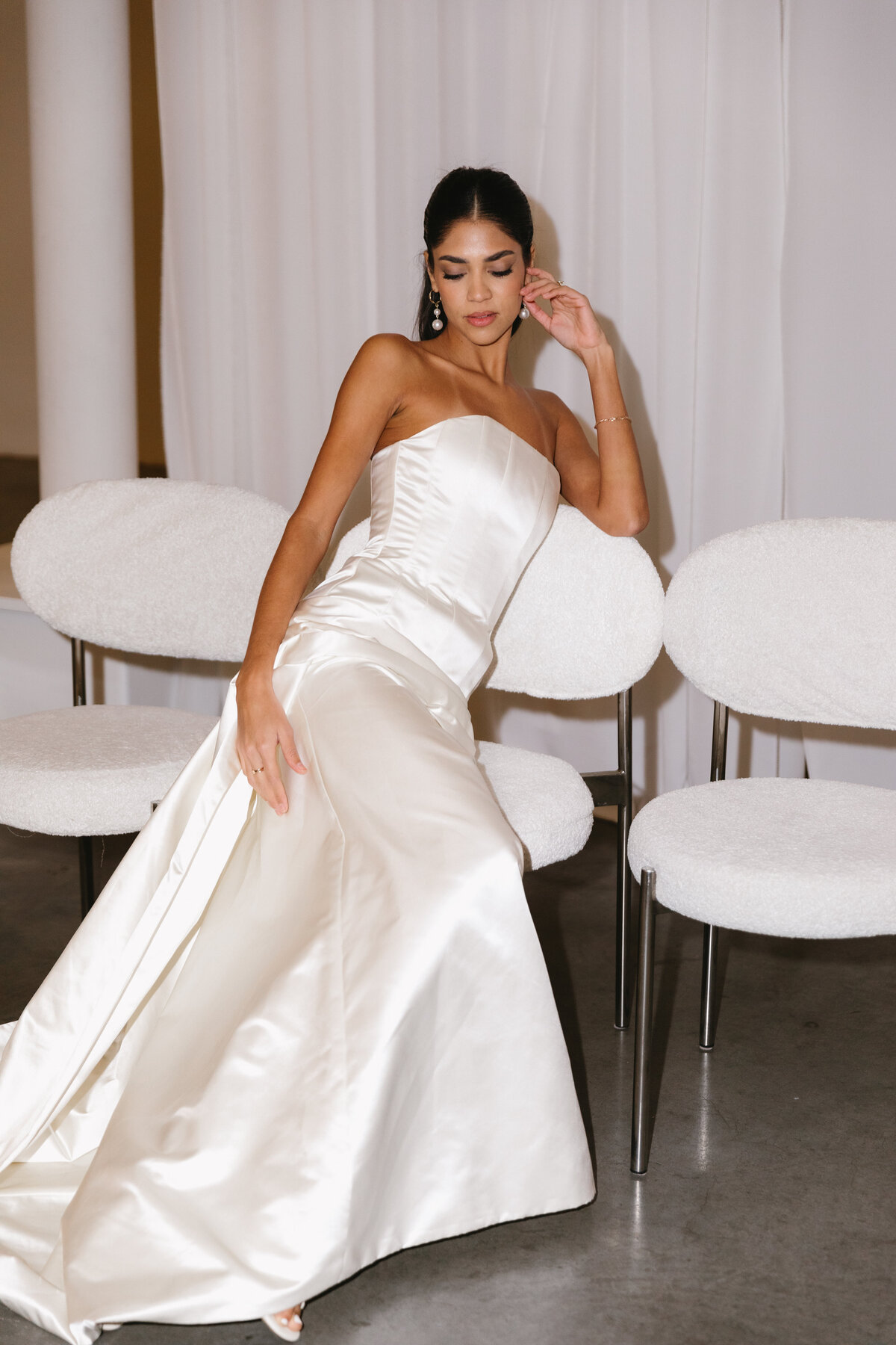Modern bride posing in an elegant satin gown with soft, elevated bridal styling.