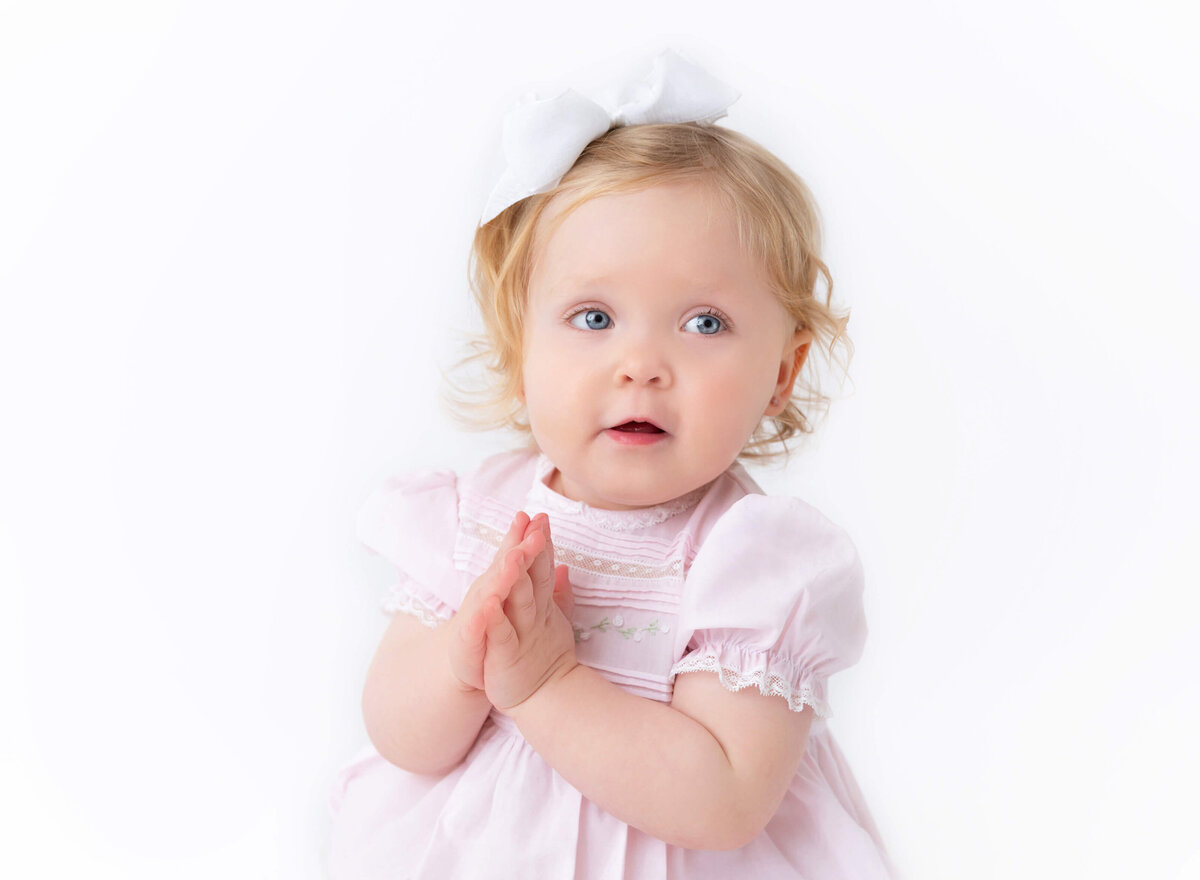 Modern Heirloom baby portrait in NYC studio — a sweet baby girl in a soft pink vintage dress with a white bow, captured by Brooklyn Heirloom photographer Rochel Konik.