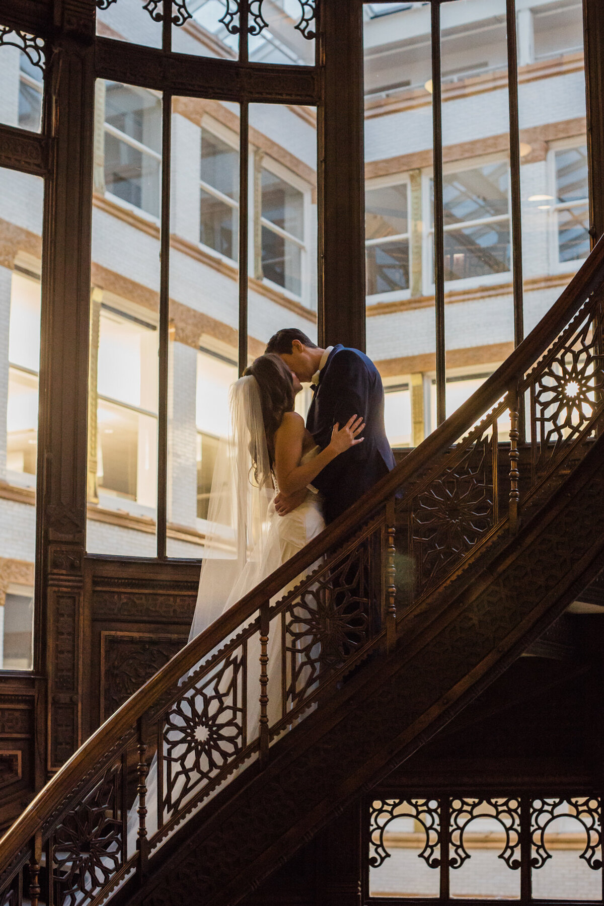 Newlyweds share a kiss in the historic staircase designed by Frank Lloyd Wright at the Rookery in Chicago
