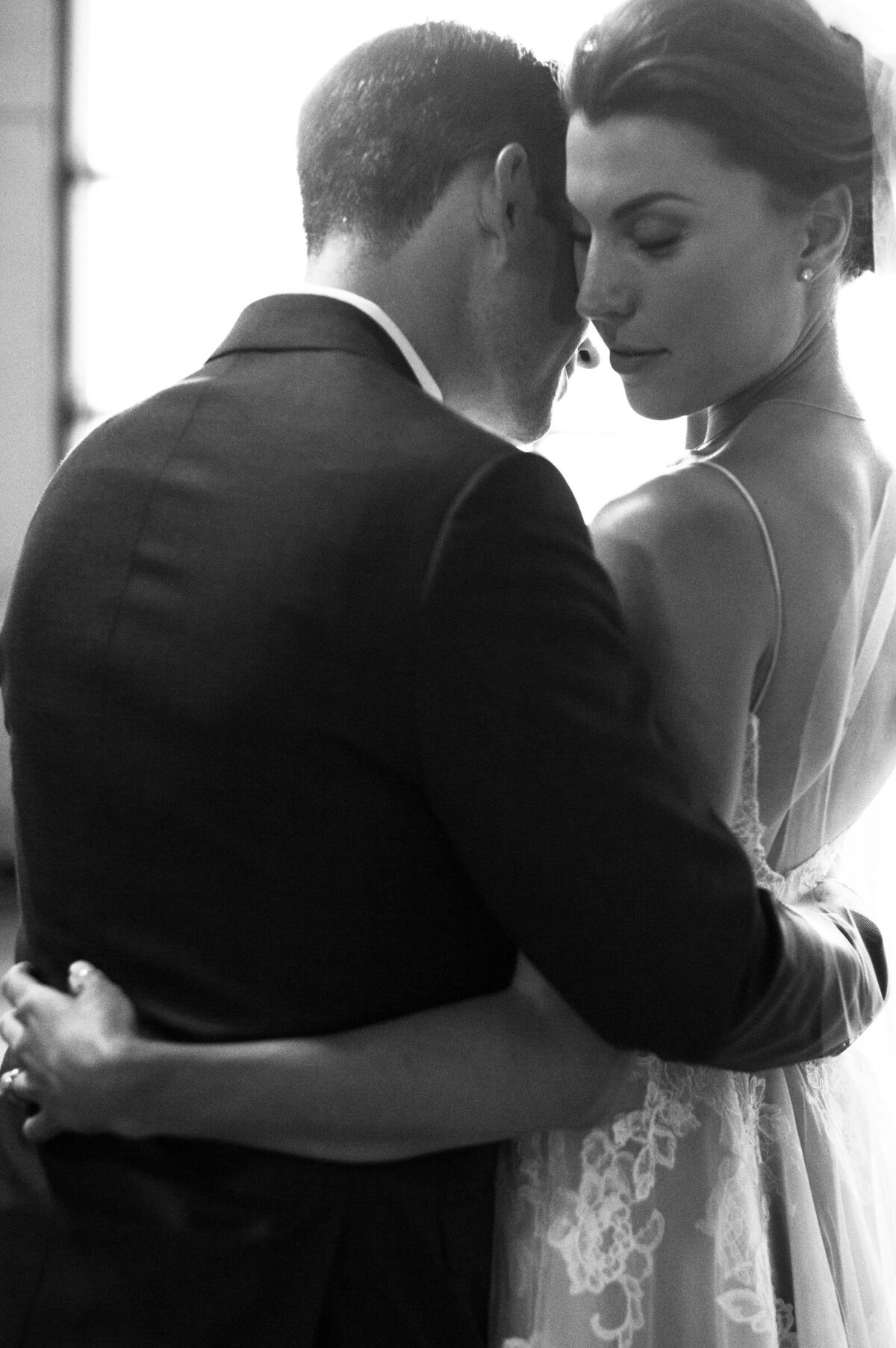 bride and groom holding each other in window light at ponzi vineyard
