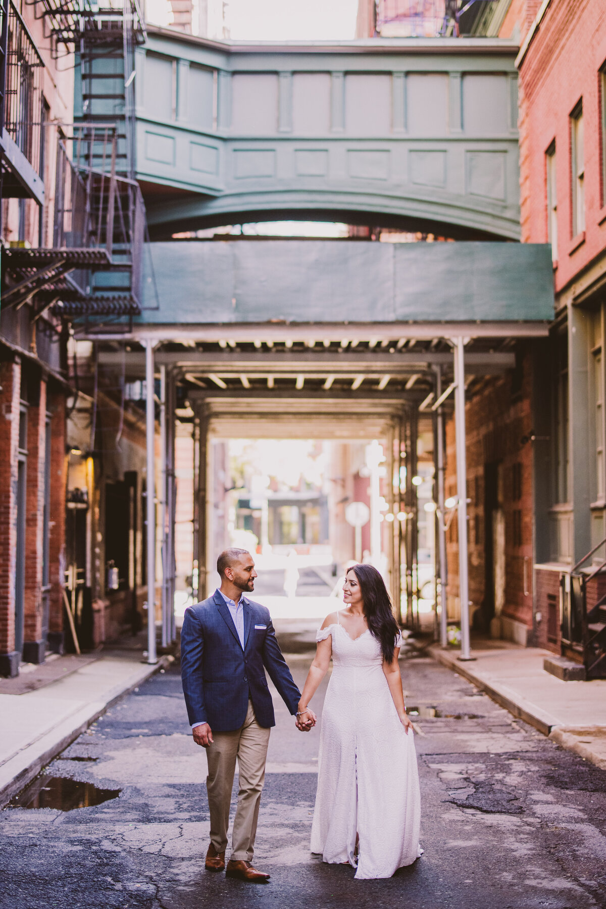 An engaged couple in white dress walking on staple street in tribeca new york