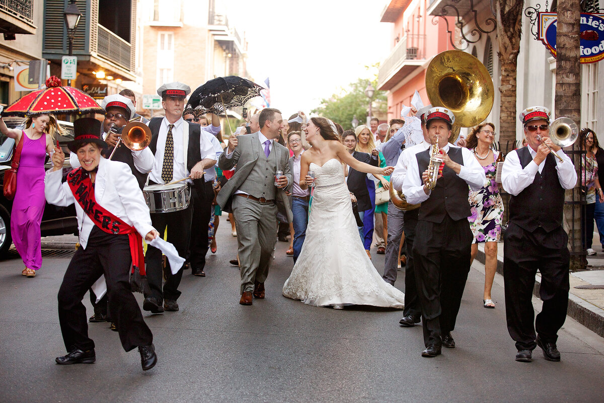 A bride and groom enjoy their second line wedding parade through the French Quarter as The Jay Walkers band leads the way in New Orleans, Louisiana.