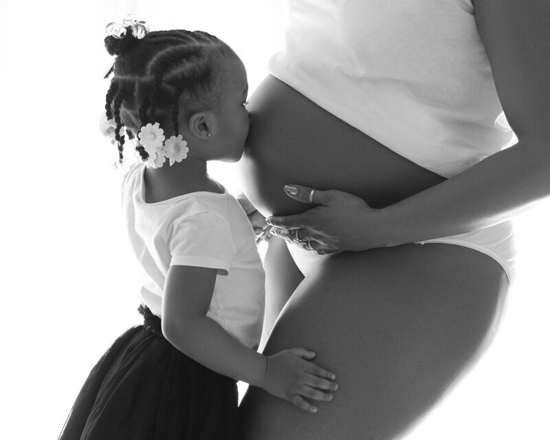 Maternity Photography with a mom and her first daughter kissing the belly by Daisy Rey