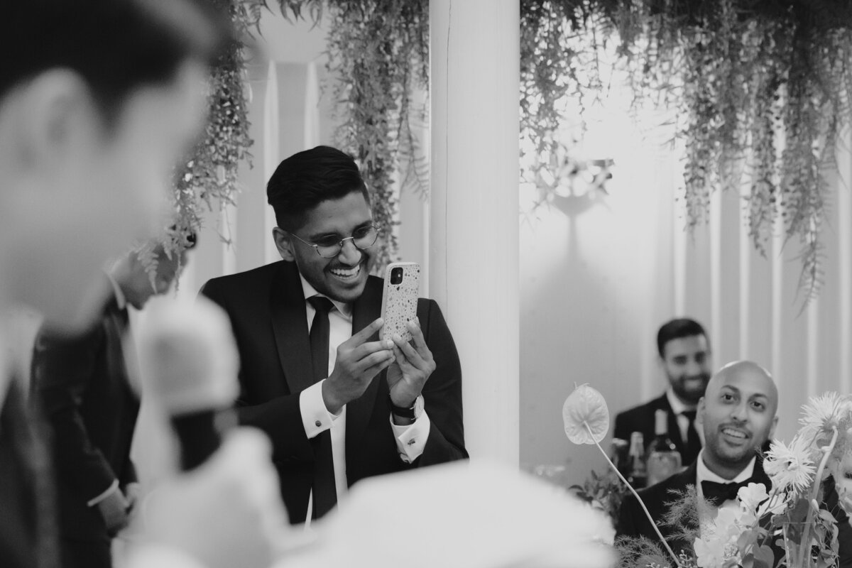 a friend taking a video of the groom's reaction to their friend's speech