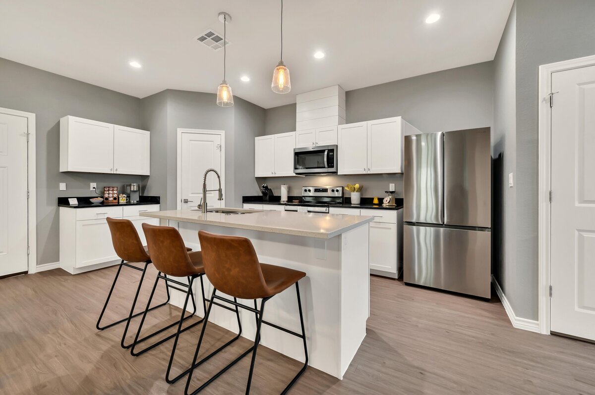 Beautiful fully stocked kitchen with island bar top seating in this four-bedroom, 4.5 bathroom new construction vacation rental house with free wifi, fire pit, gazebo, cornhole, private bathrooms for each bedroom within walking distance of Magnolia and Baylor in downtown Waco, TX.