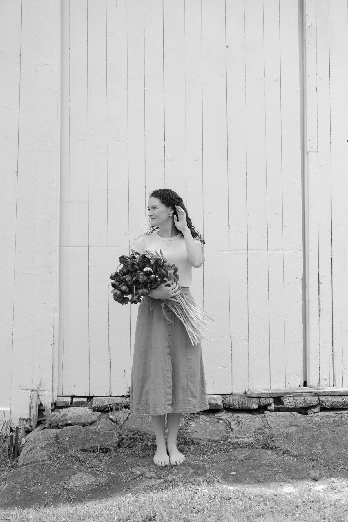 Florist holding bouquet of wildflowers in front of barn doors.