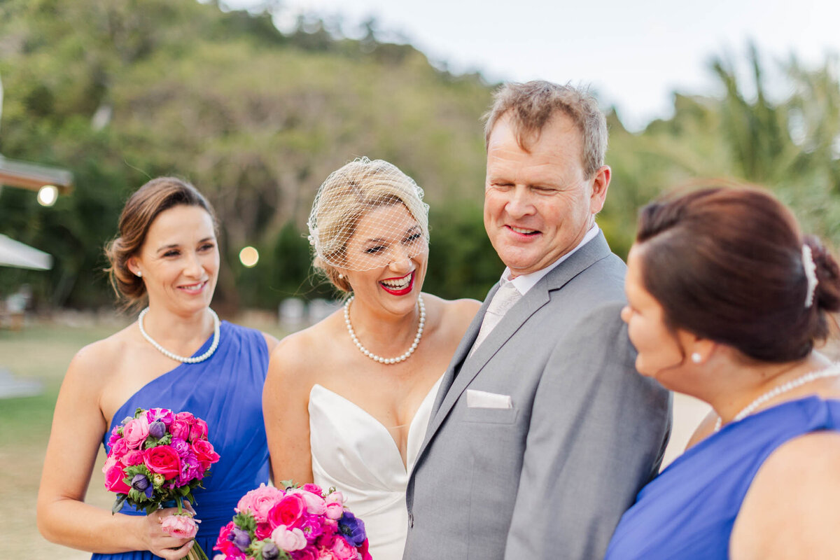 Brian laughs over at bridesmaid during party portraits at Airlie beach wedding