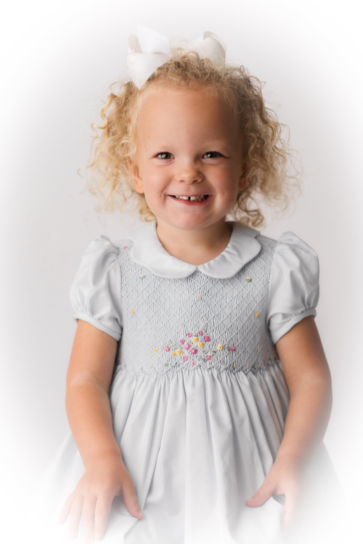 Little girl smiles into the camera during Heirloom Portrait Session in Charleston, SC Photo Studio.
