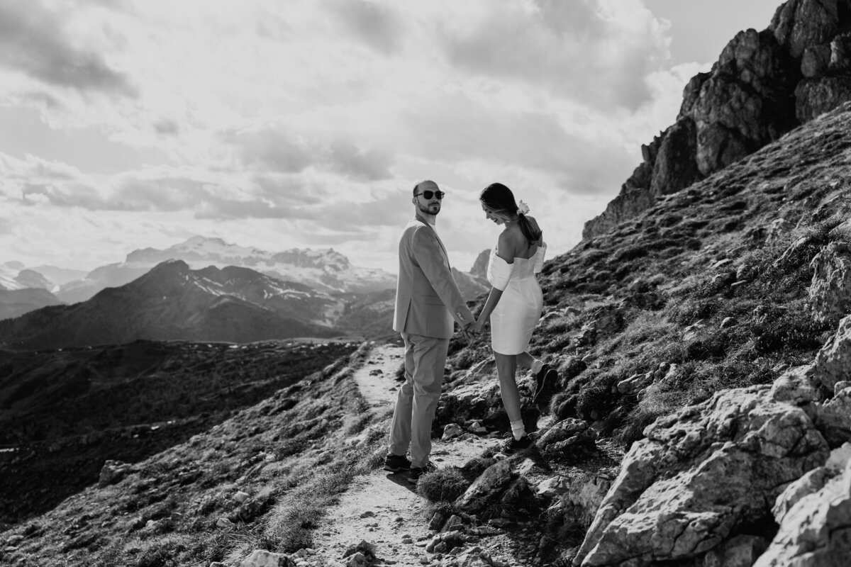 Black and white photo of couple holding hands on rocky mountain path