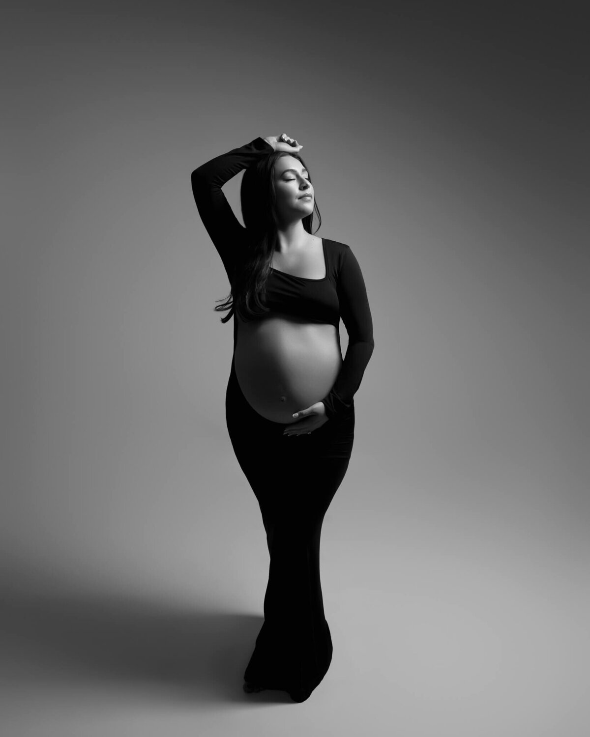 pregnant woman in empowering maternity photoshoot pose holding her belly