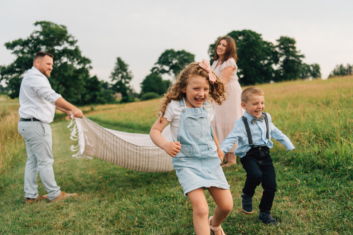 Family of four playing with blanket in field