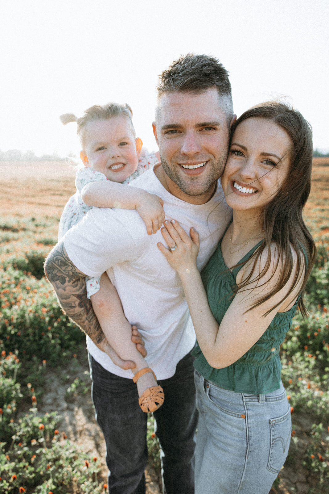 Family of three hug each other in the golden hour sunlight in Oregon. 