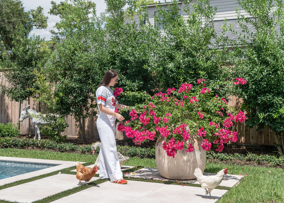 Megan working on a flower with chickens walking beside her