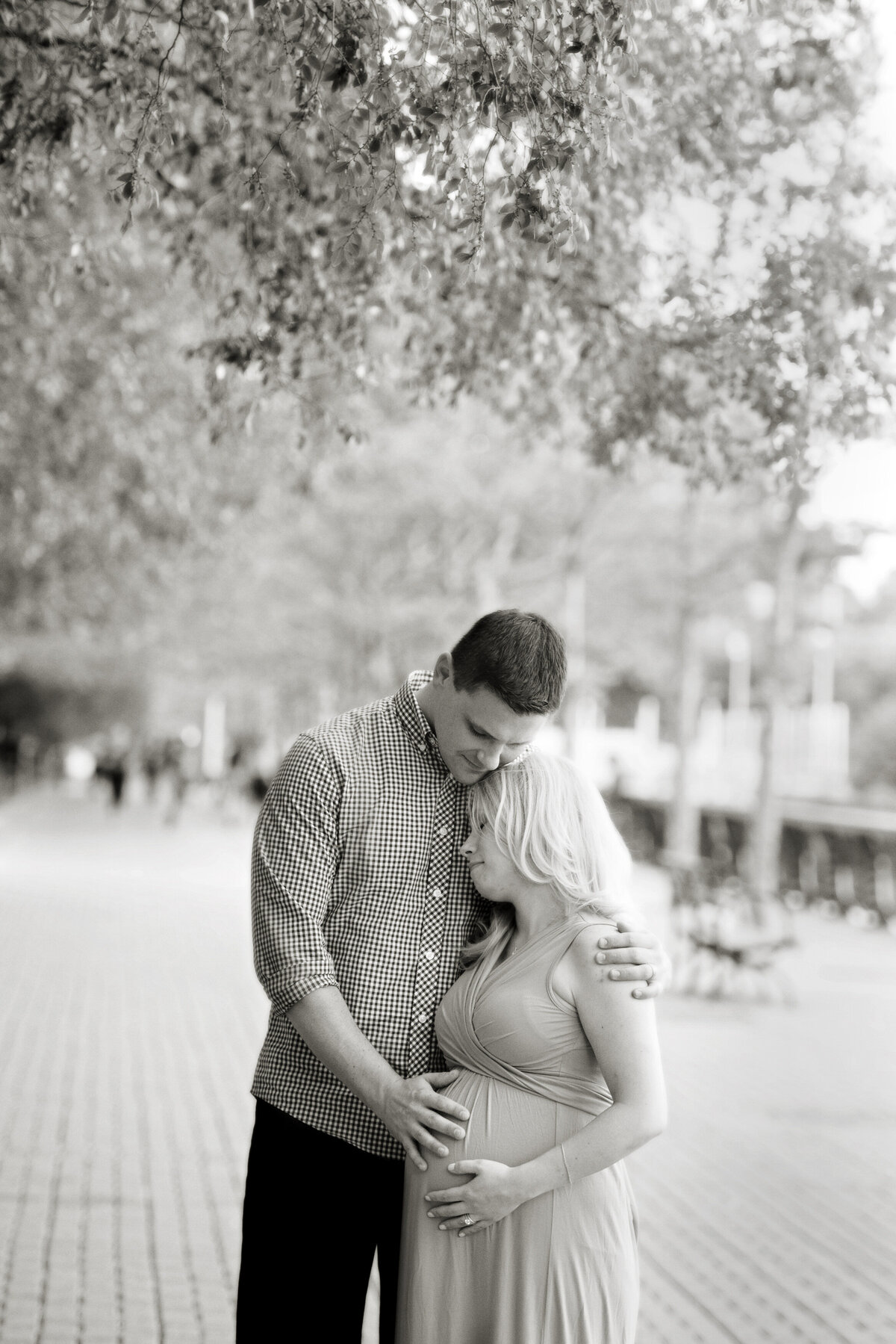 A pregnant couple hugging as they each hold the baby bump 