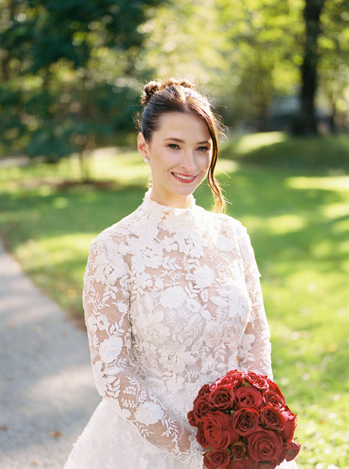 Bride wearing lace dress and carrying red bouquet by Halifax wedding photographer, Alyssa Joy Photography