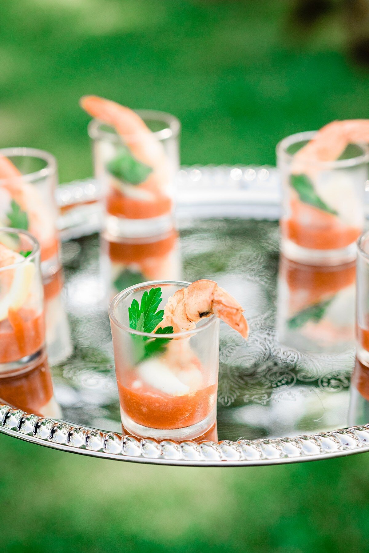 Shrimp cocktail shooters on a silver planner being served by Chef Penelope's Catering at a Nashville wedding.