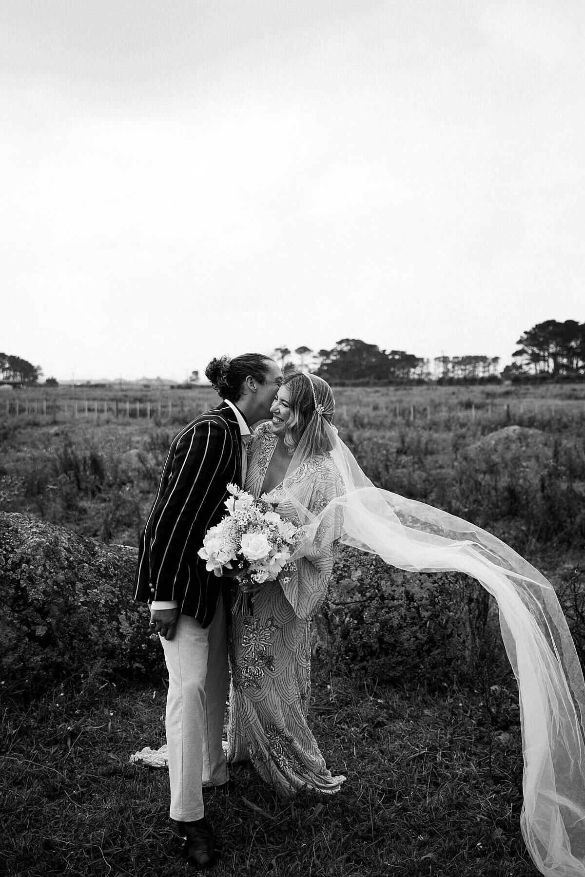 A bride and groom standing in a field during their photoshoot with taranaki wedding photographer aimee kelly photography