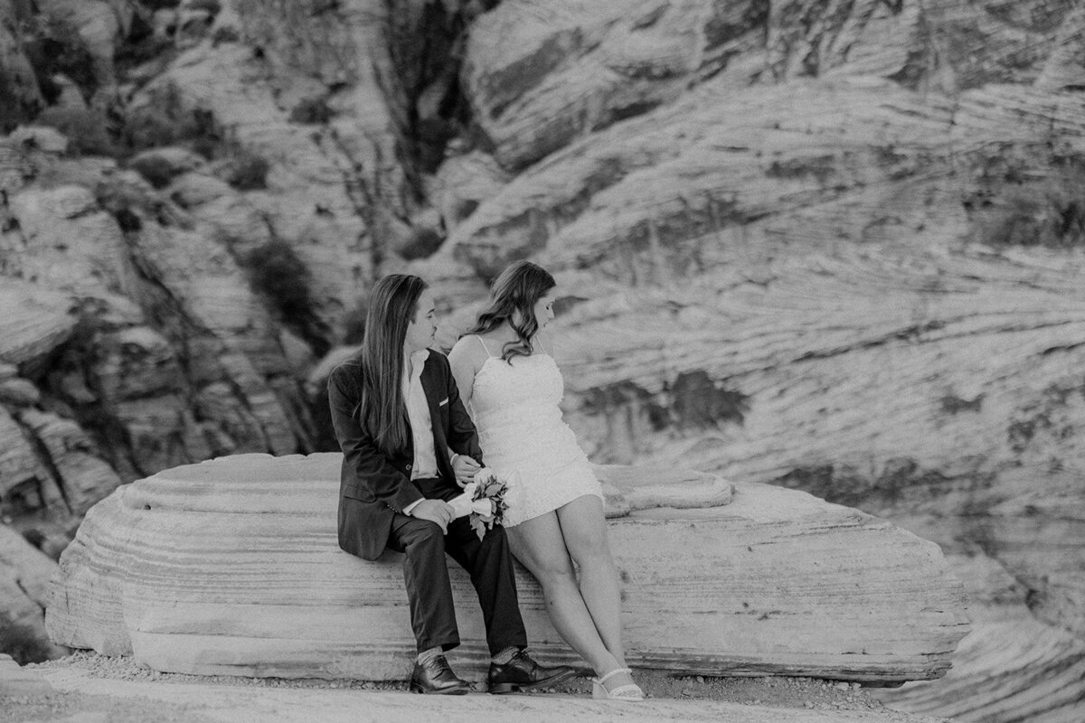 Engaged couple sitting on rock at the Red Rock Canyon smiling