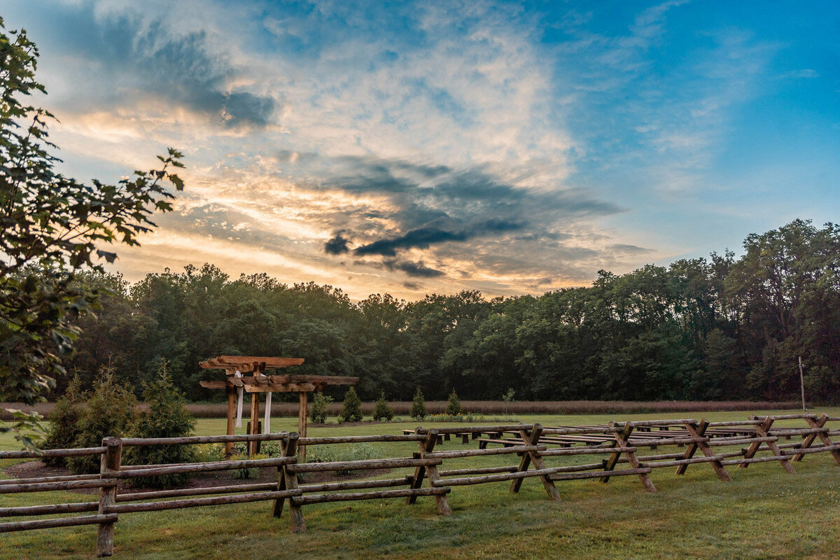 Scenic view of the pergola and fence at sunset with trees in the background