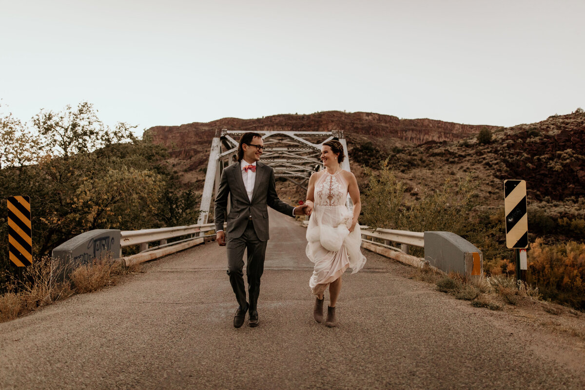 bride and groom running on a bridge
