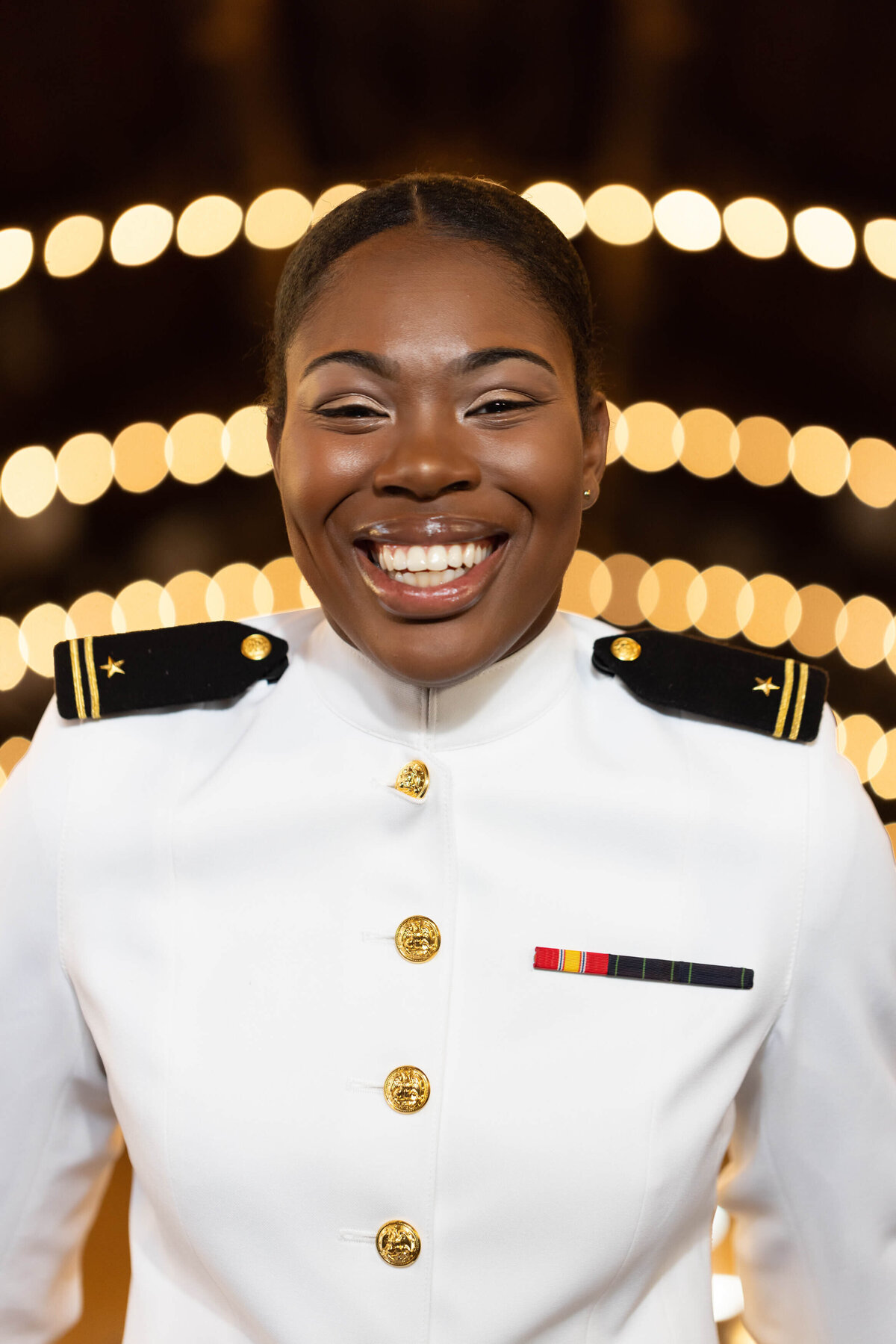 USNA Midshipman smiles in Dahlgren Hall and Naval Academy with beautiful lights.