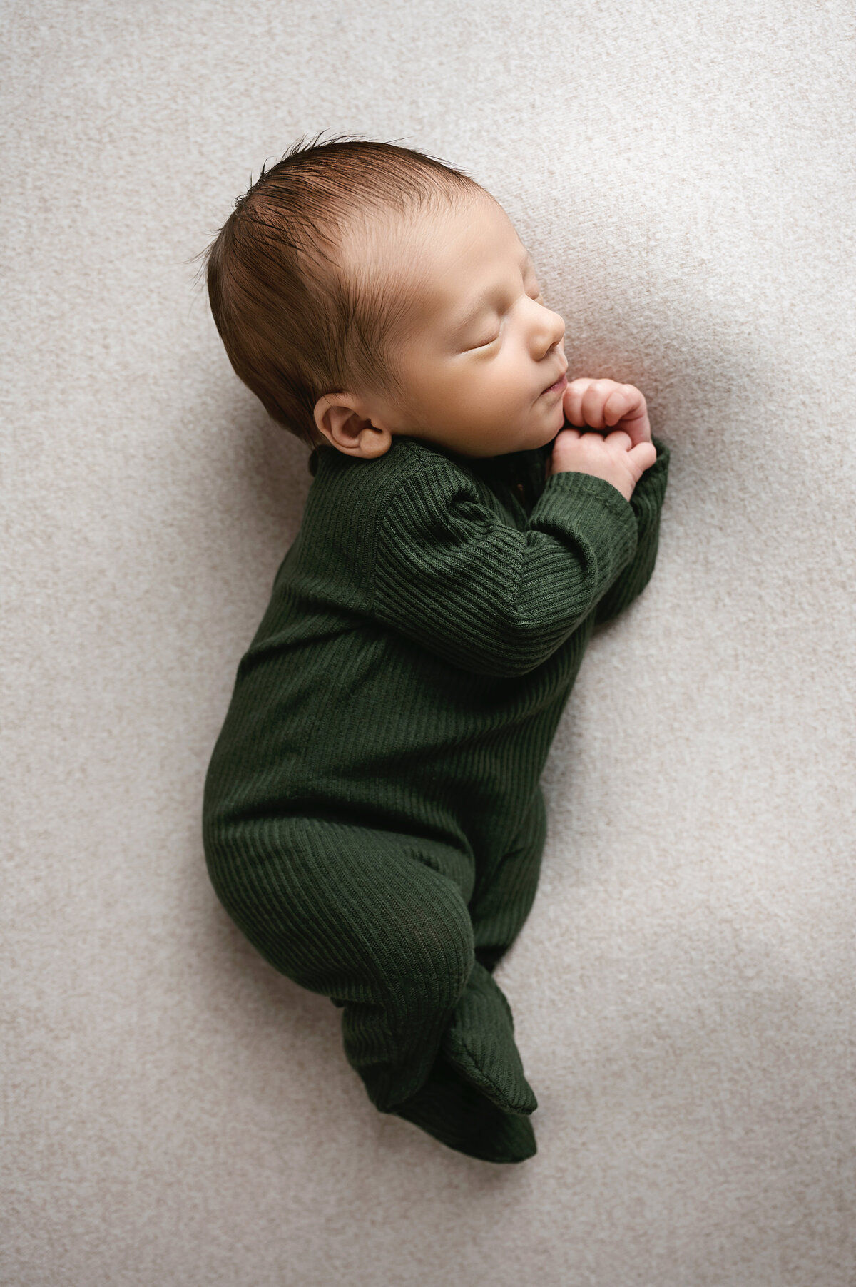 A charming moment captured of a peaceful baby boy in a cozy green outfit. Let our Pittsburgh newborn photographer preserve these adorable moments for you forever.