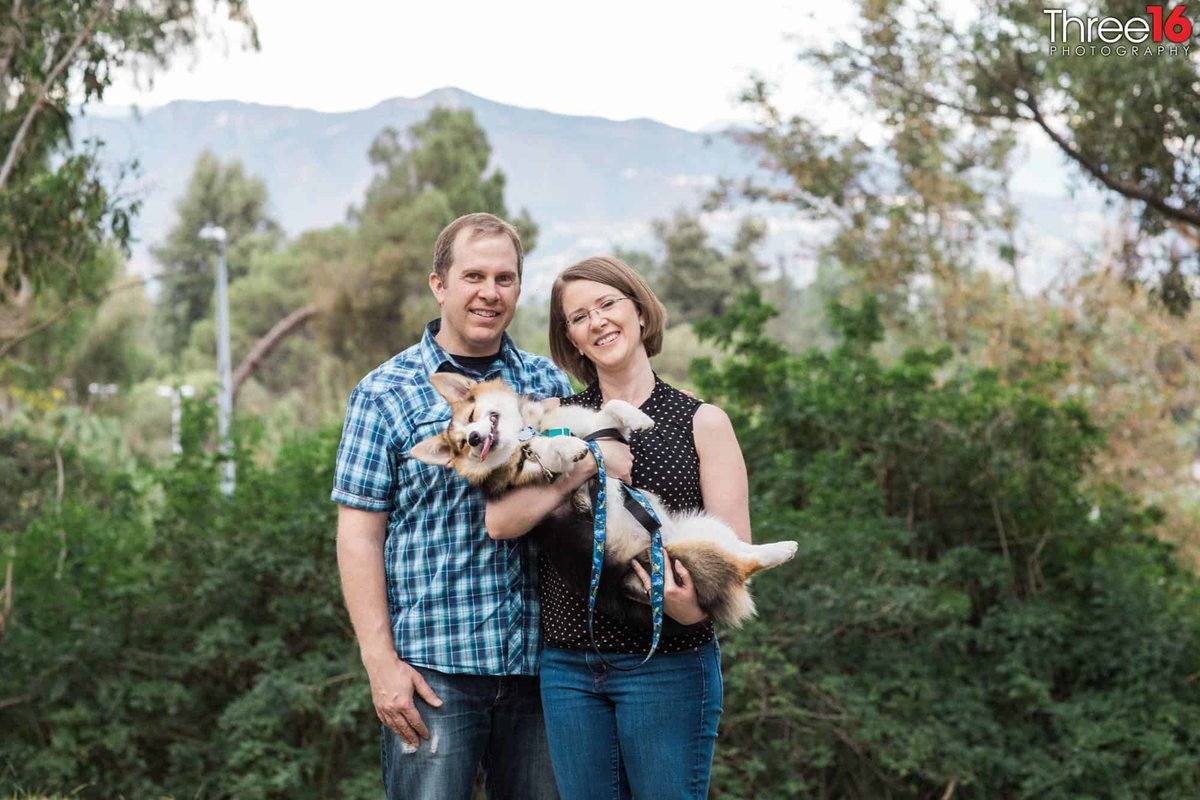 Engaged couple pose for photos with their dog in hand